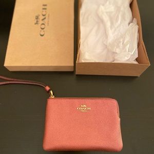 Coach wristlet in pink with gold detailing. 5.5” x 3.5”